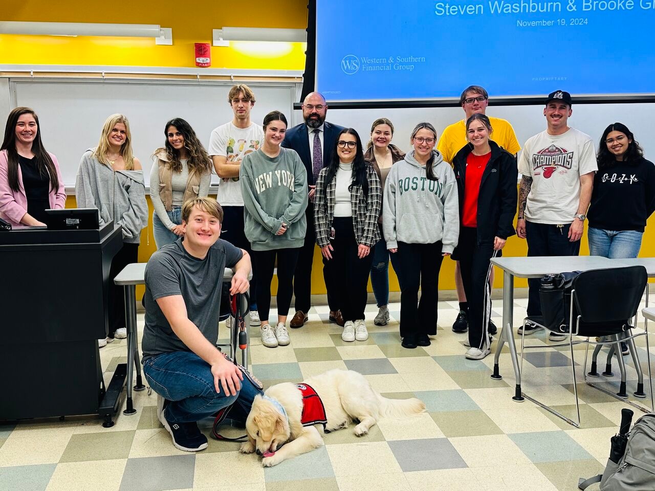 UC students in classroom pose with professor and employer speaker